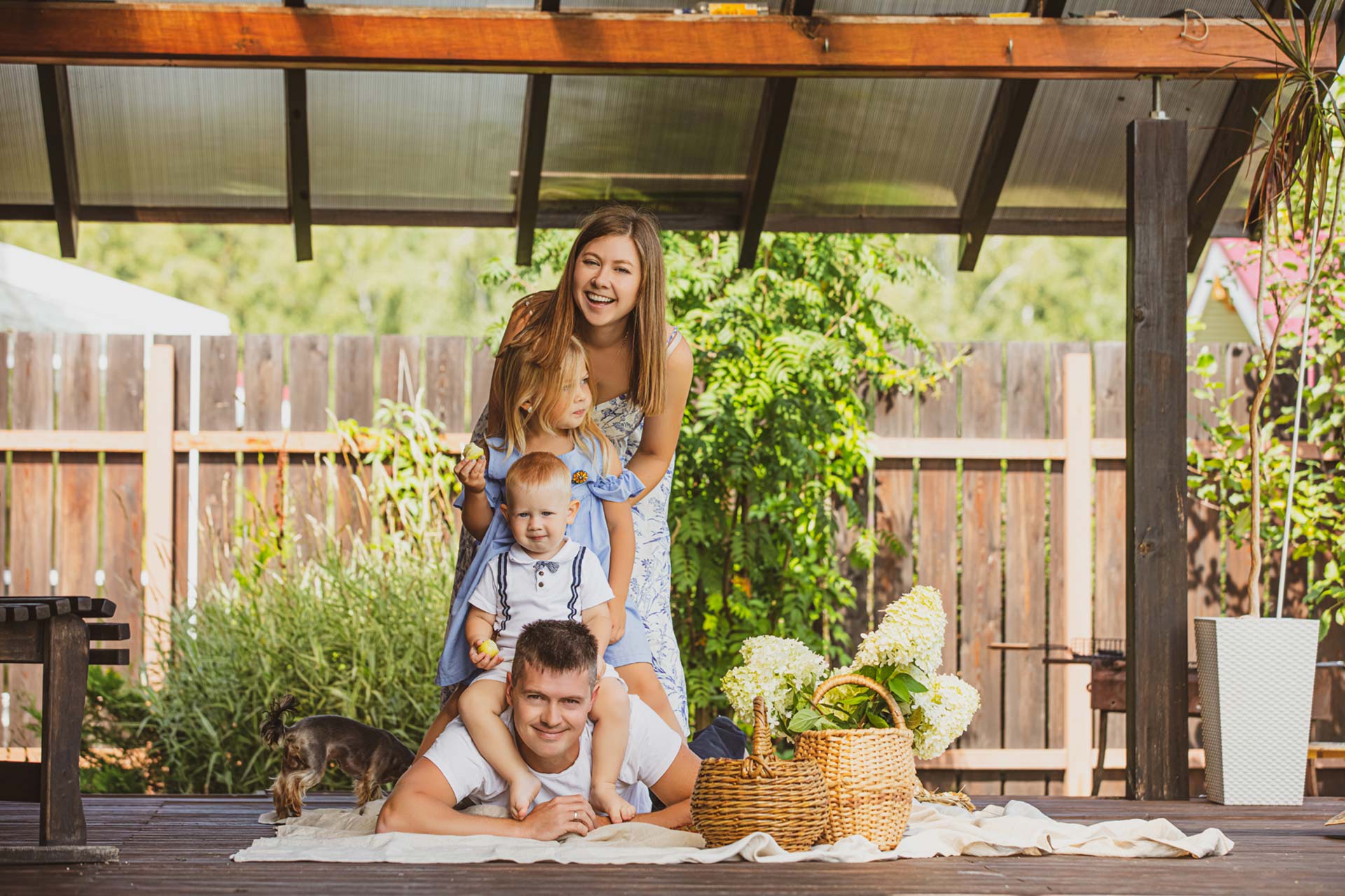 Glückliche Familie genießt gemeinsame Zeit unter einer modernen Terrassenüberdachung mit Holzstruktur.