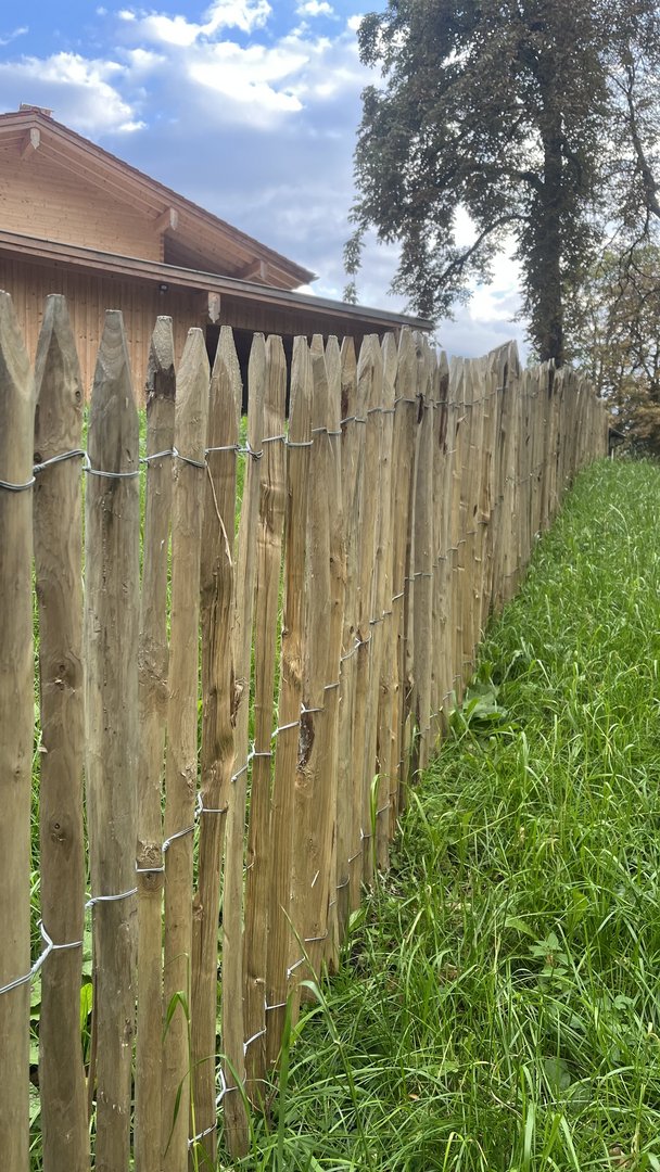 Ein Staketenzaun im Garten eines Kunden von Holz Steinsdorfer im Ammertal
