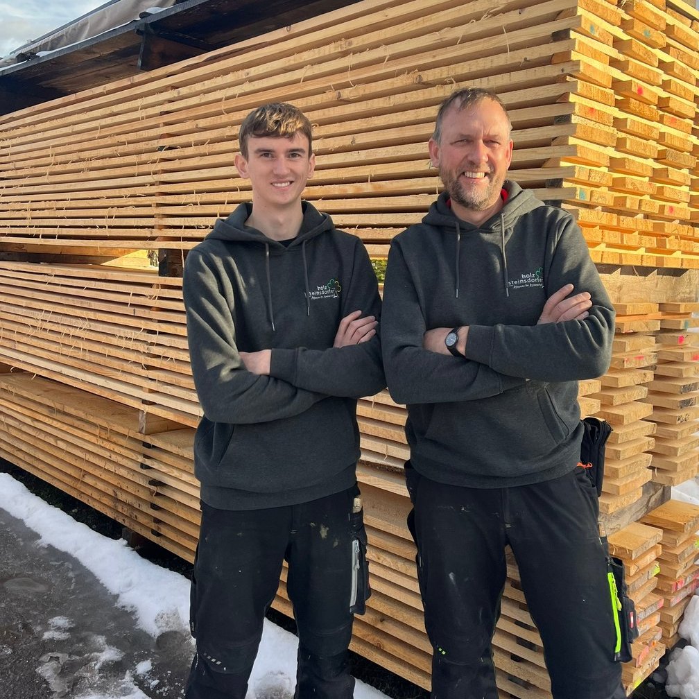 Mitarbeiter von Holz Steinsdorfer vor gestapeltem Bauholz im Sägewerk im Ammertal