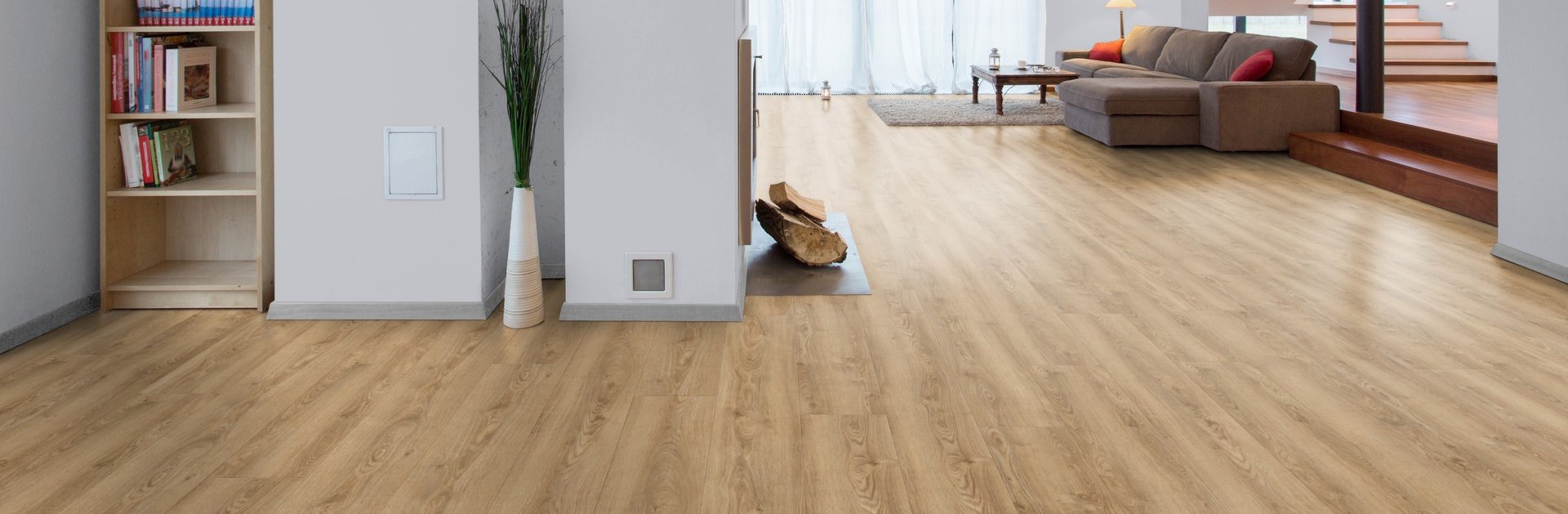 Ein großer offener Wohnraum mit Flur, Wohnbereich und Treppenaufgang mit einem Vinylboden in Holzoptik verlegt