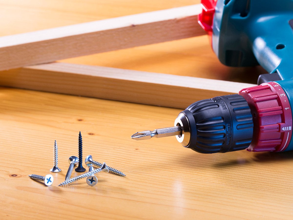 Akkuschrauber mit Holzschrauben auf einer Holzoberfläche für präzise Montagearbeiten im Holzbau