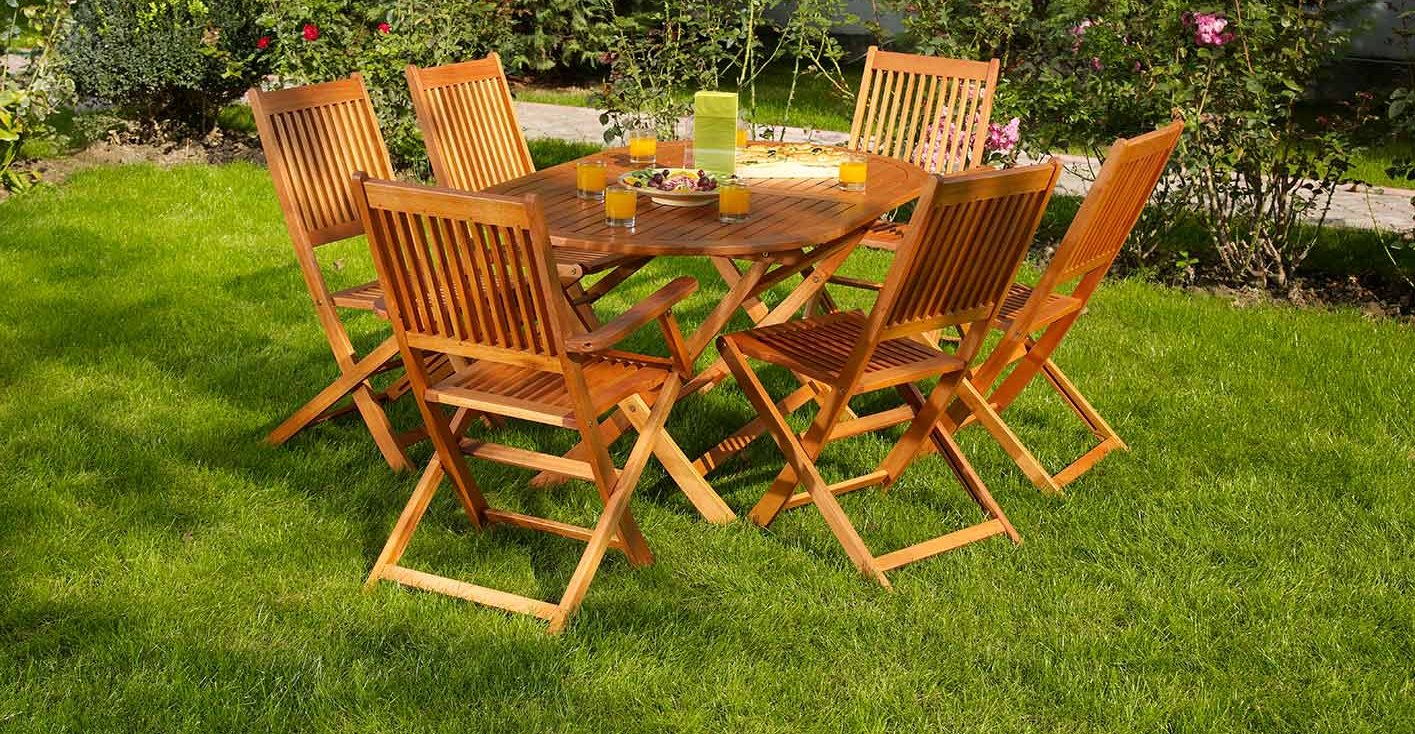 Eine gemütliche Sitzgruppe mit Holztisch und Stühlen auf der Wiese im Garten 