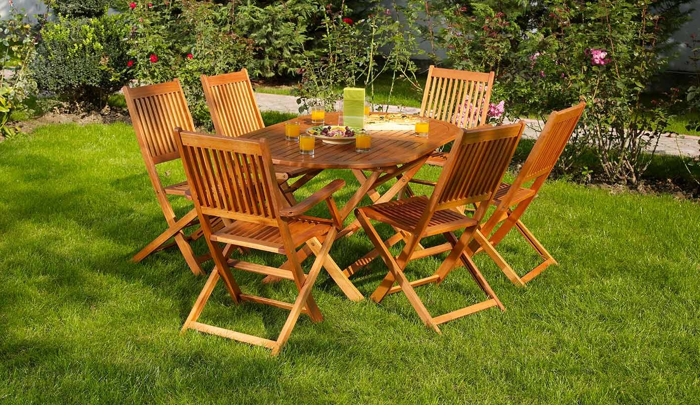Eine gemütliche Sitzgruppe mit Holztisch und Stühlen auf der Wiese im Garten 