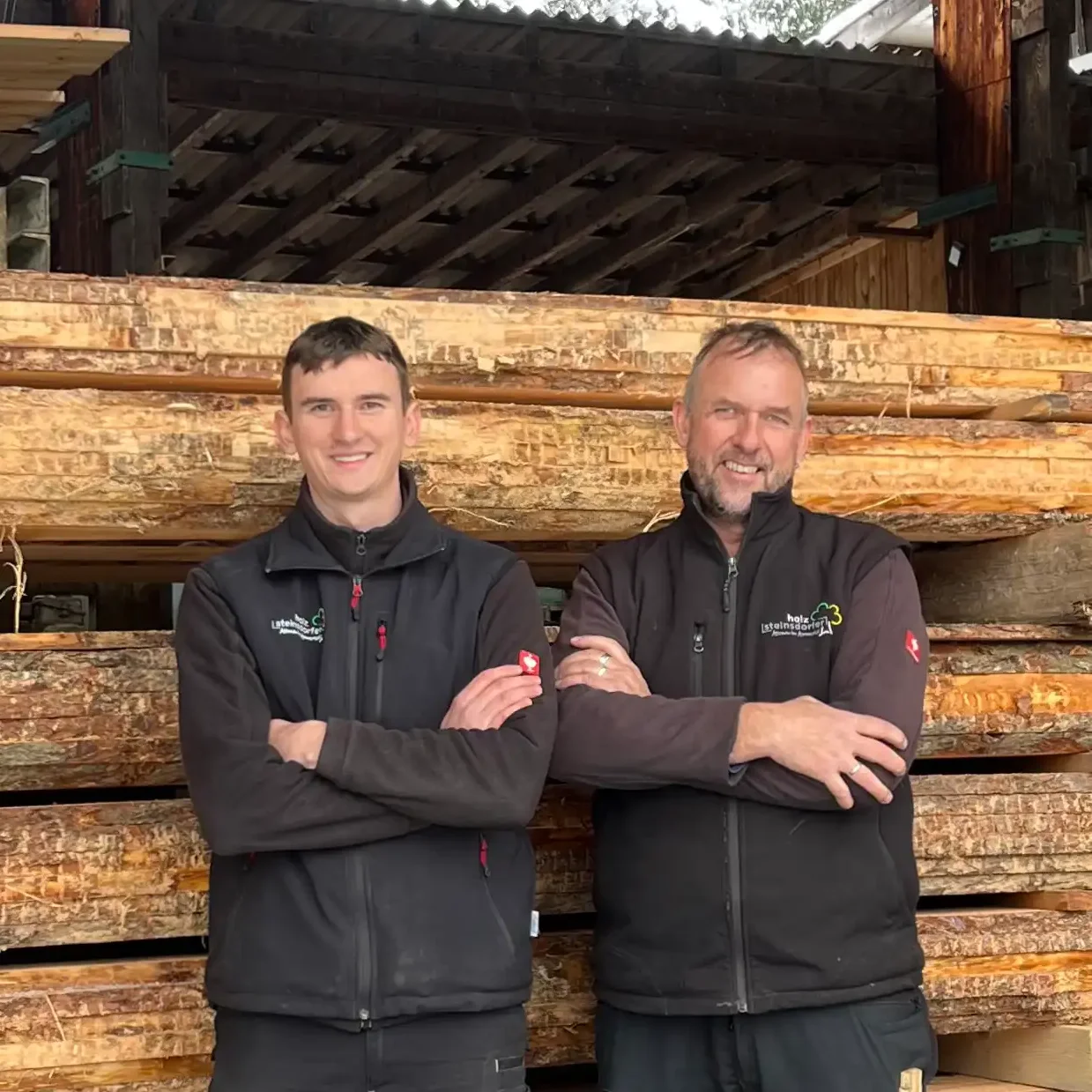 Steinsdorfer Junior und Senior Markus vor frisch gelagerten Rundhölzern im eigenen Sägewerk