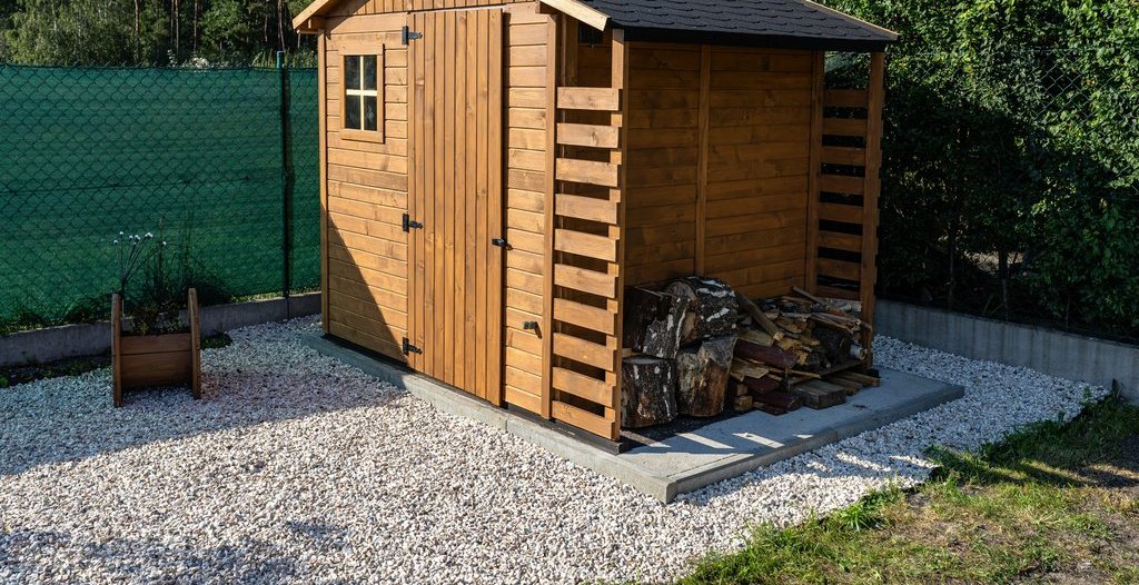 Ein dunkelbraunes kleines Gartenhaus mit Kaminholzlager