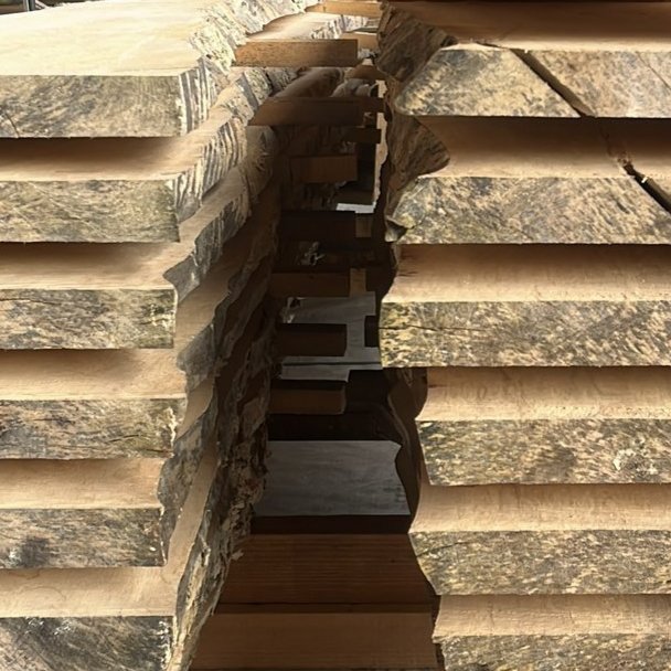 Gestapelte, frisch gesägte Holzbohlen aus dem eigenen Sägewerk