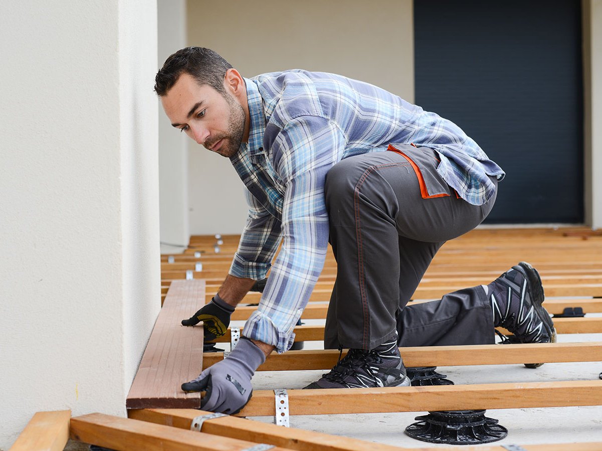 Handwerker montiert Terrassendielen auf einer stabilen Holzunterkonstruktion